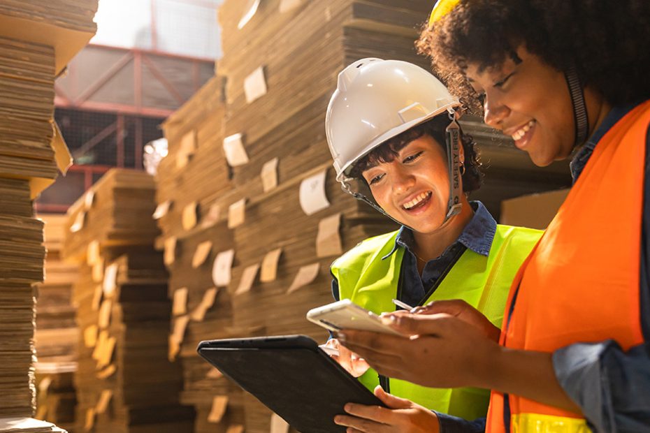 workers in industrial packaging area using phones and tablets
