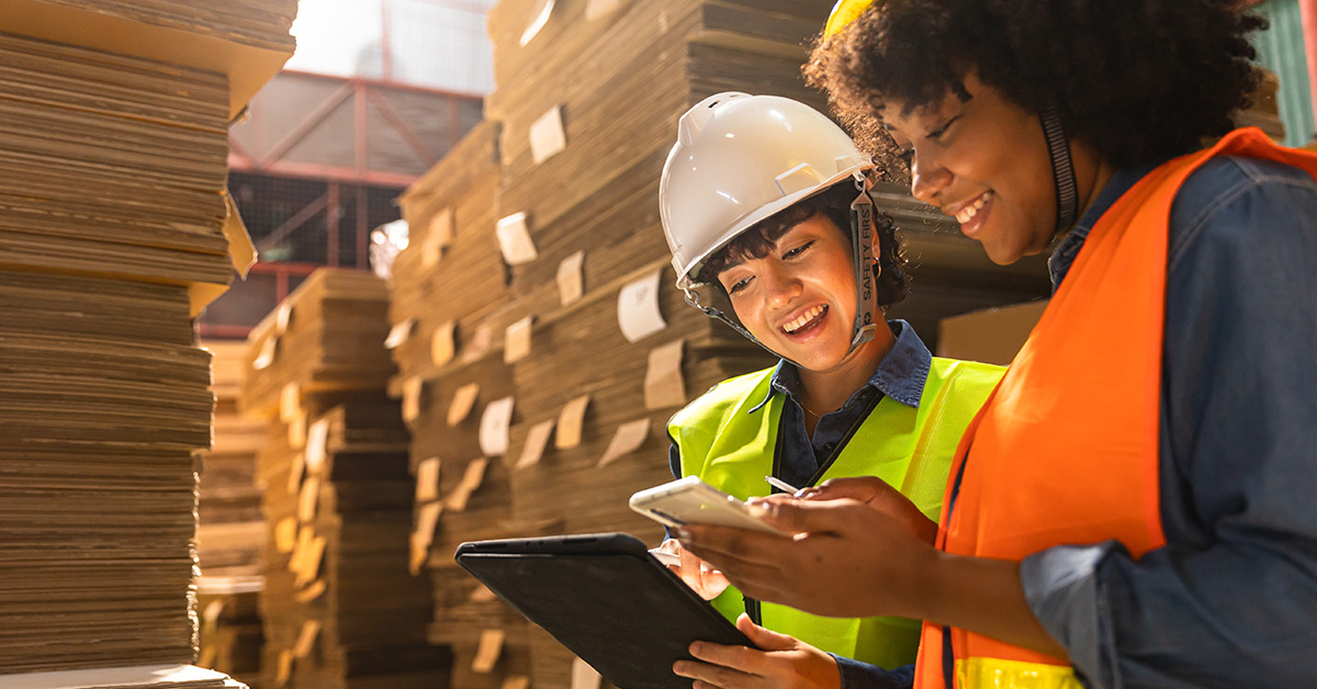 workers in industrial packaging area using phones and tablets
